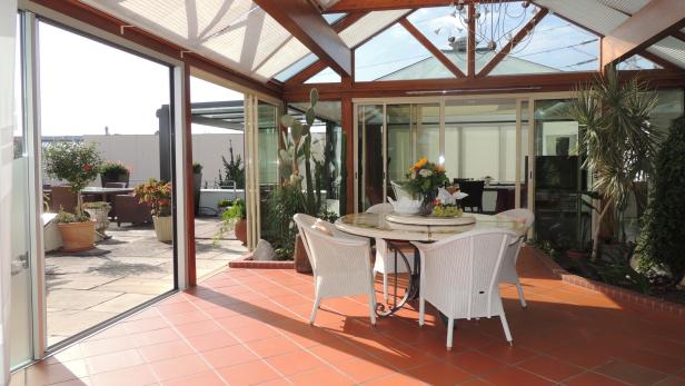 Ein Wintergarten mit einem Esstisch und Blick auf eine Terrasse.