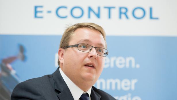 Ein Mann mit Brille spricht vor einem Banner von E-Control.