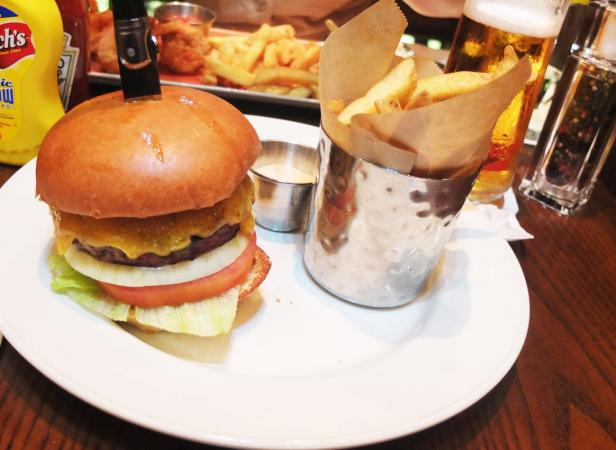 Ein Burger mit Pommes Frites und einem Bier auf einem Tisch.