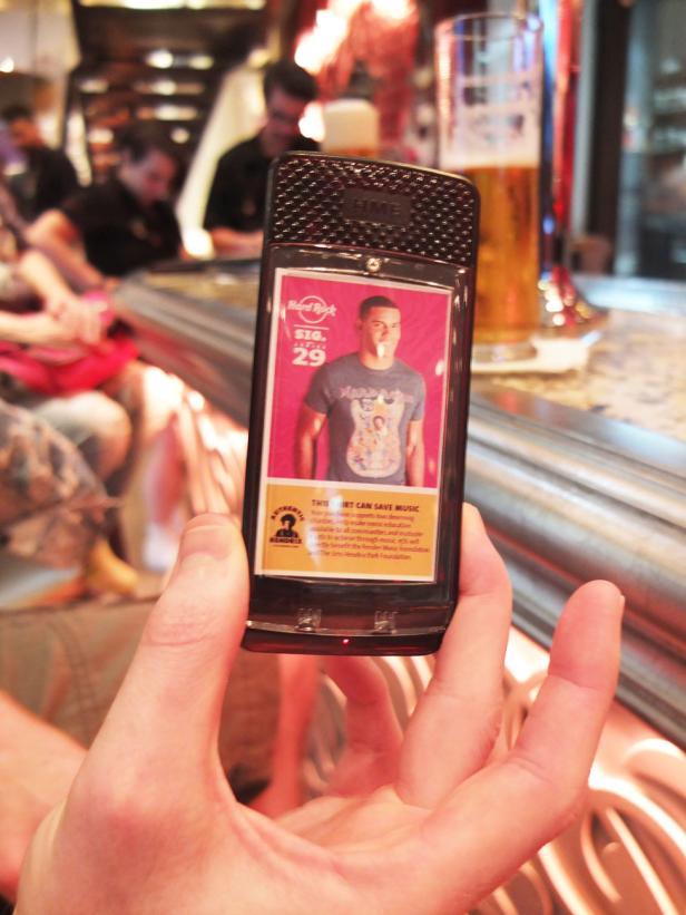 Eine Person hält ein Hard Rock Cafe Feuerzeug mit dem Bild eines Mannes auf einem T-Shirt.