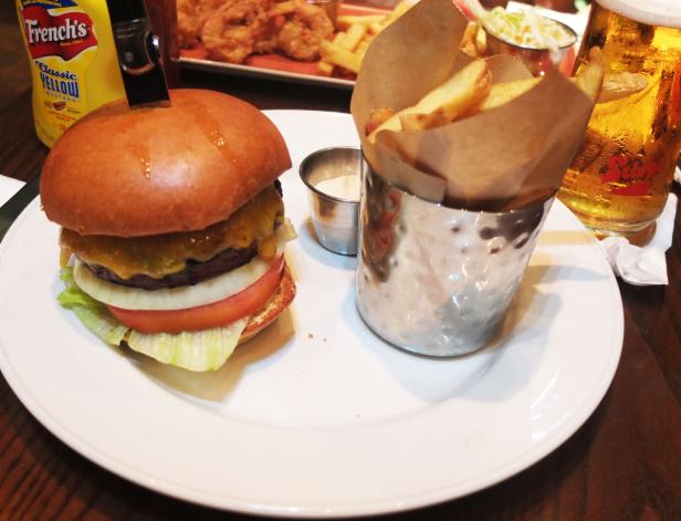 Ein Cheeseburger mit Pommes Frites und einem Glas Bier auf einem Teller.