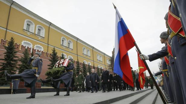 Soldaten in Paradeuniform tragen einen Kranz und die russische Flagge auf dem Roten Platz.