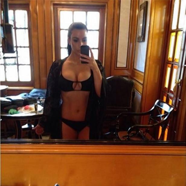 Eine Frau macht ein Selfie von sich im Bikini vor einem Spiegel.