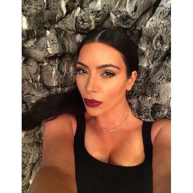 Ein Porträt von Kim Kardashian mit dunklem Lippenstift auf einem Fellteppich.