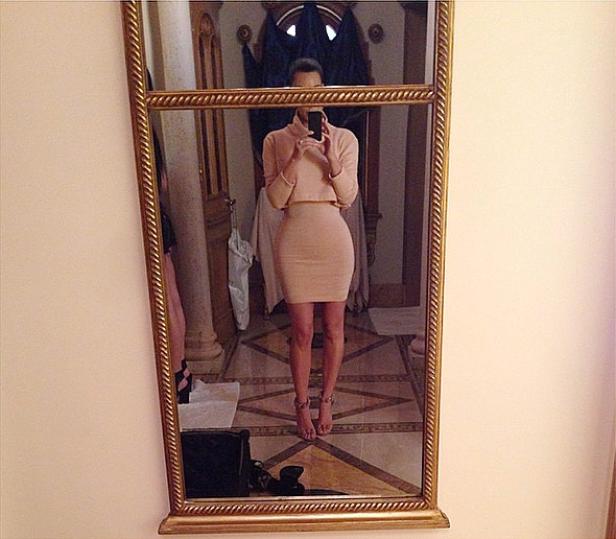 Eine Frau macht ein Selfie von sich im Spiegel, gekleidet in ein rosafarbenes Outfit.