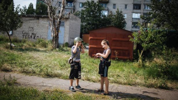 Zwei Jungen spielen im Freien, einer trägt einen Helm.
