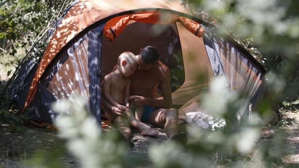 Ein Vater umarmt seinen Sohn im Zelt.