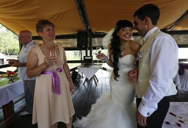 Ein Brautpaar steht auf einer Hochzeit, während Gäste mit Champagner anstoßen.