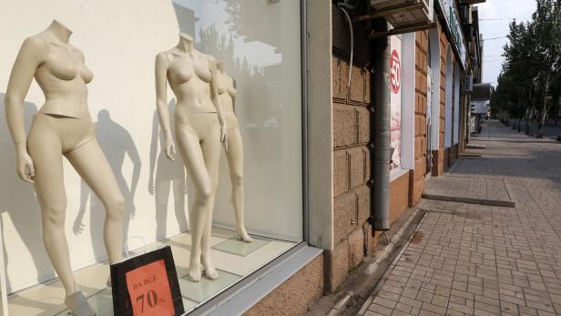 Drei Schaufensterpuppen in Unterwäsche stehen in einem Schaufenster mit einem 70%-Rabatt-Schild.