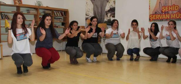 Eine Gruppe junger Frauen hockt auf dem Boden und klatscht in die Hände.