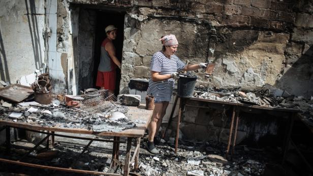 Eine Frau räumt in einer zerstörten Küche Trümmer weg.