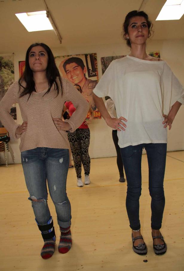 Zwei junge Frauen posieren mit Händen in den Hüften in einem Raum.