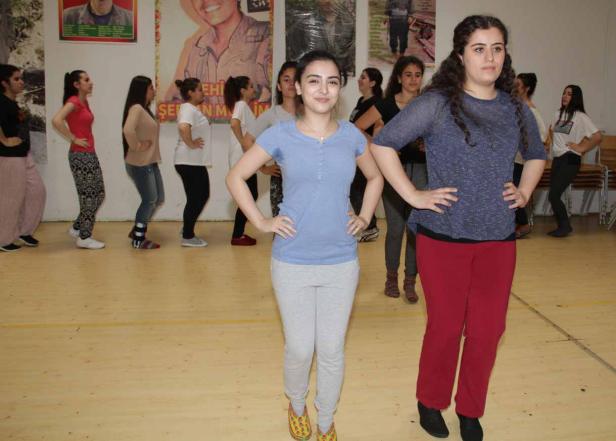 Eine Gruppe junger Frauen steht in einem Raum mit Postern an der Wand.