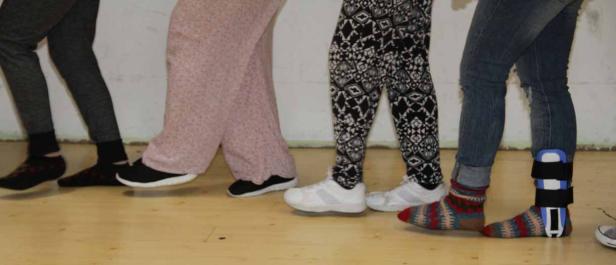 Eine Reihe von Personen, von denen man nur die Beine sieht, stehen nebeneinander.