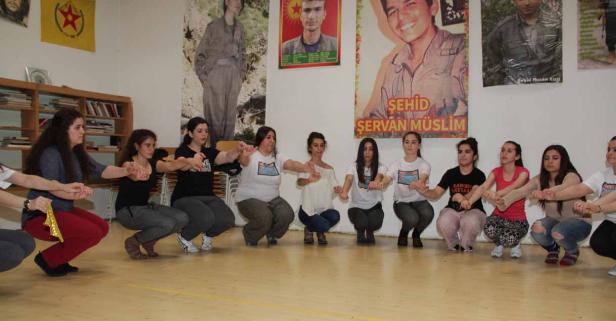 Eine Gruppe junger Frauen hockt im Kreis und hält sich an den Händen.