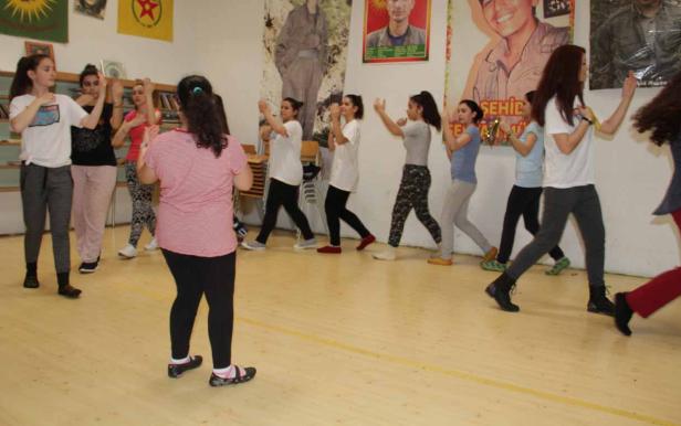 Eine Gruppe junger Frauen übt gemeinsam eine Choreografie in einem Raum.