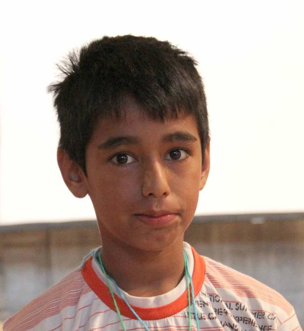 Ein junger Mann mit dunklen Haaren und einem gestreiften T-Shirt blickt in die Kamera.