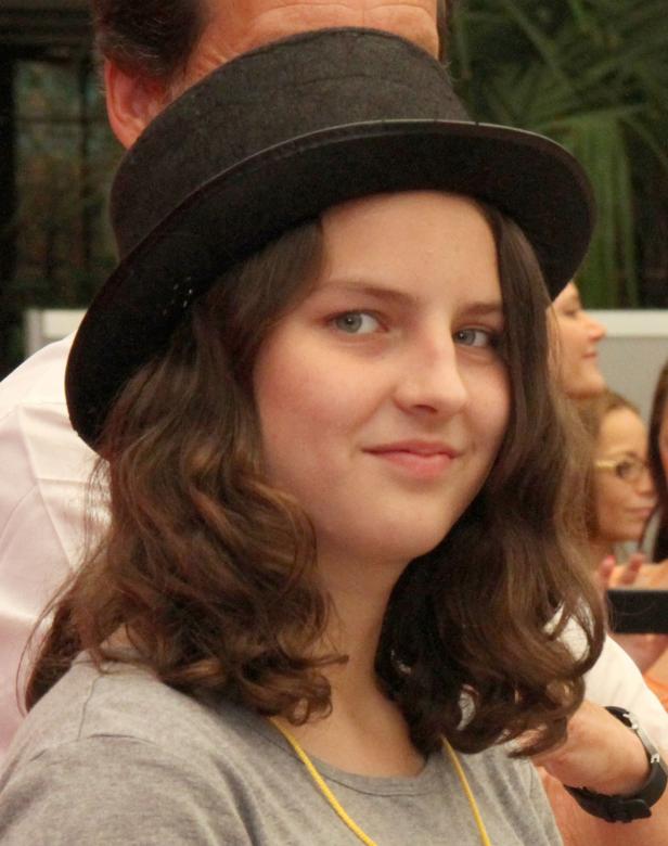 Eine junge Frau mit Hut lächelt in die Kamera.