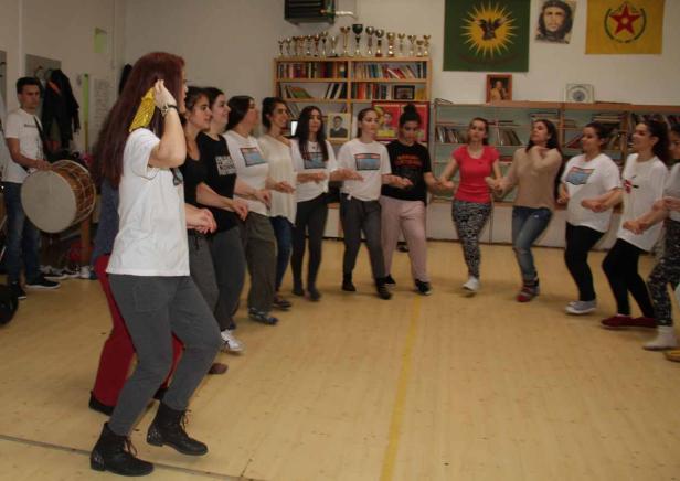 Eine Gruppe von Frauen tanzt im Kreis, begleitet von einem Trommler.