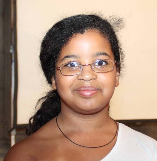 Ein junges Mädchen mit Brille lächelt in die Kamera.