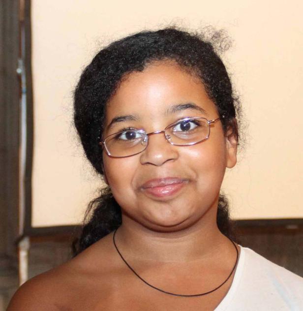 Ein Porträt eines jungen Mädchens mit Brille und dunklen Haaren.