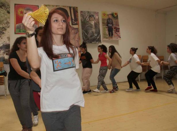 Eine Gruppe junger Frauen tanzt im Kreis, eine hält ein gelbes Tuch hoch.