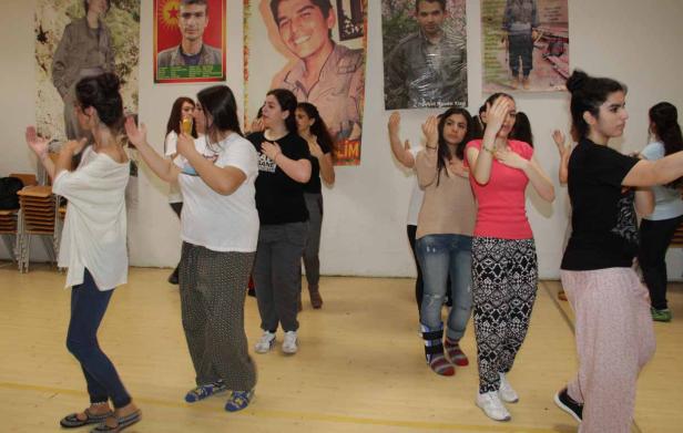 Eine Gruppe junger Frauen tanzt in einem Raum mit Porträts an der Wand.