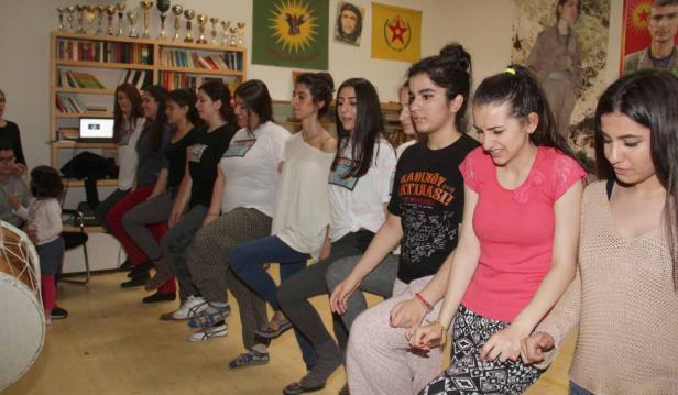 Eine Gruppe junger Frauen sitzt in einer Reihe und hält Händchen.