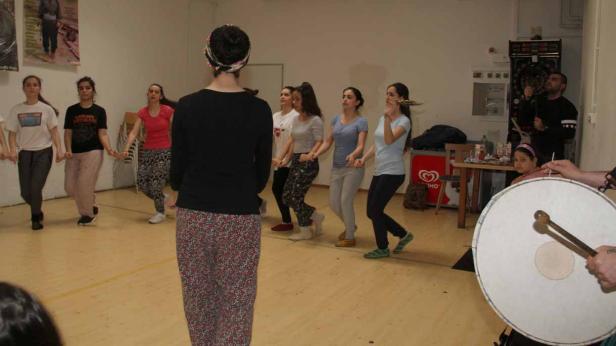 Eine Gruppe junger Frauen tanzt zu traditioneller Musik in einem Raum.