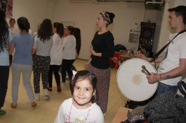 Eine Gruppe von Menschen, darunter ein Mädchen im Vordergrund, mit einem Mann, der eine Trommel spielt.