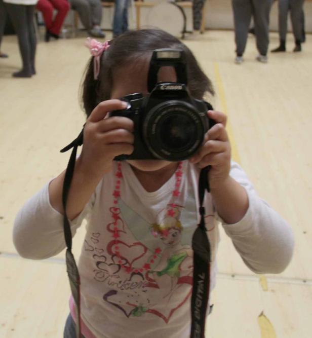 Ein junges Mädchen fotografiert mit einer Spiegelreflexkamera.