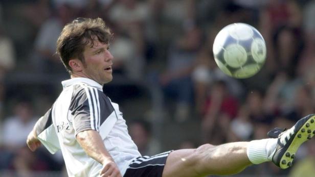 Ein Fußballspieler schießt einen Ball vor einer Zuschauermenge.