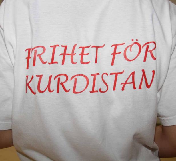 Auf der Rückseite eines weißen T-Shirts steht in roter Schrift „Frihet för Kurdistan“.