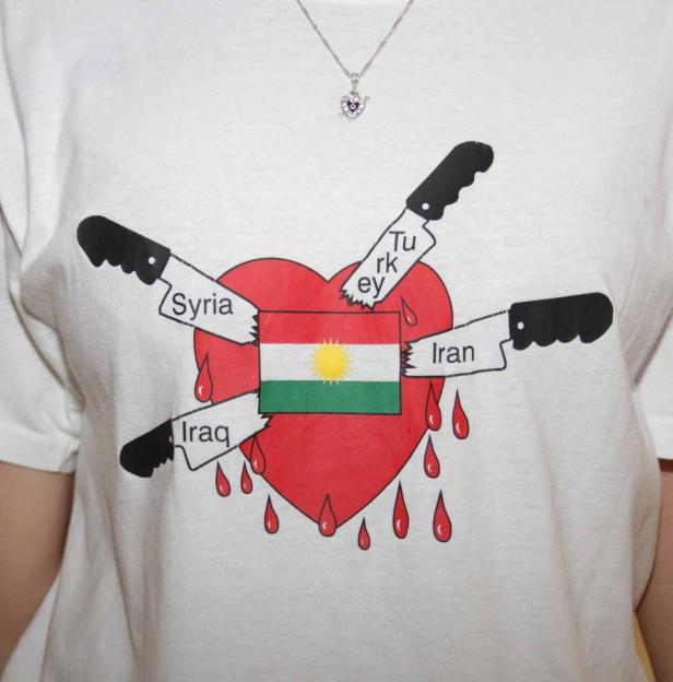 Ein T-Shirt mit einem roten Herz, der Flagge Kurdistans und vier Messern mit den Aufschriften Syrien, Irak, Iran und Türkei.