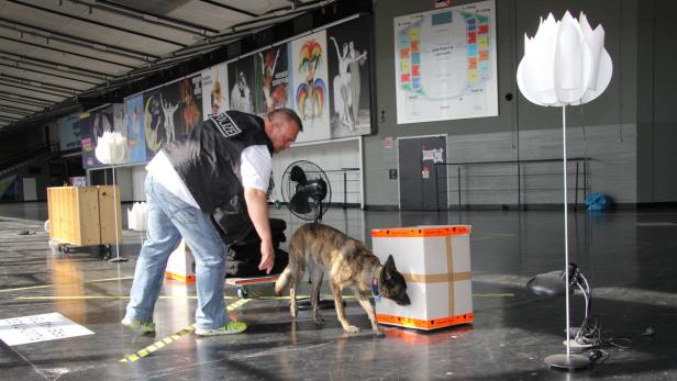 Ein Polizist mit einem Spürhund untersucht eine Kiste.