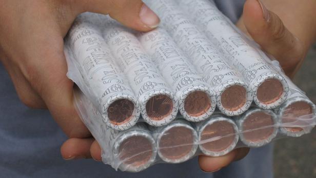 Eine Hand hält eine Packung mit Rollen von 1-Cent-Münzen.