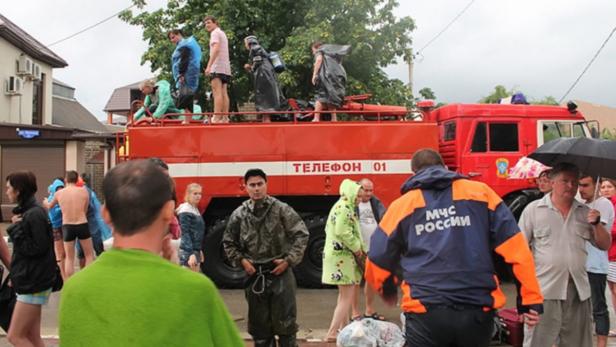 Menschen stehen nach einer Überschwemmung auf einem Feuerwehrwagen.