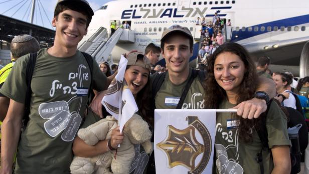 Junge Leute stehen vor einem El Al-Flugzeug und feiern ihre Einwanderung nach Israel.