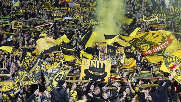 Gelbe und schwarze Fahnen werden von Fans von Borussia Dortmund im Stadion geschwenkt.