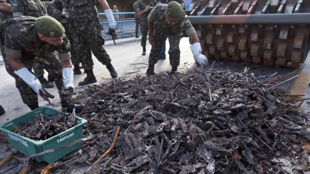 REUTERSArmy troops prepare 40,000 destroyed weapons to mark the International Day of Arms Destruction at the Sambadrome in Rio de Janeiro July 9, 2012. The goal of the symbolic event is to promote awareness among the population as Rio officials step up th Soldaten sammeln zerstörte Waffen vor einer Walze ein.
