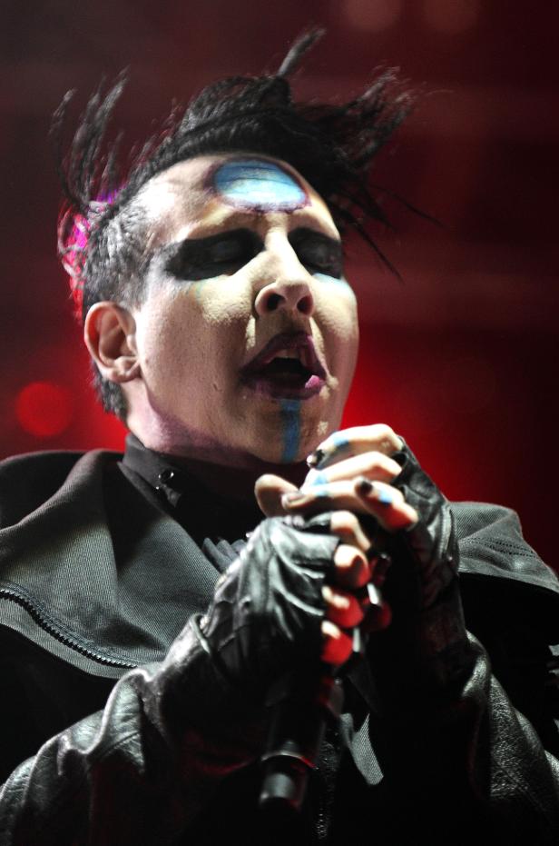 Marilyn Manson singt mit auffälligem Make-up in ein Mikrofon.