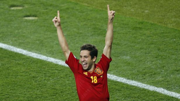 Ein spanischer Fußballspieler jubelt mit erhobenen Armen auf dem Rasen.