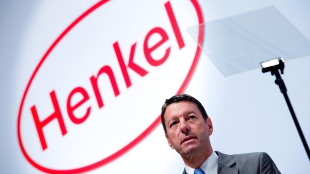 Ein Mann steht vor einem großen Henkel-Logo auf einer Bühne.