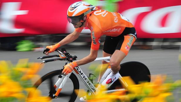 Ein Radrennfahrer in orangefarbener Teamkleidung fährt ein Zeitfahren.