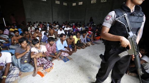 INDONESIA ACEH MIGRATION Ein bewaffneter Polizist bewacht eine Gruppe sitzender Männer in einem Raum.