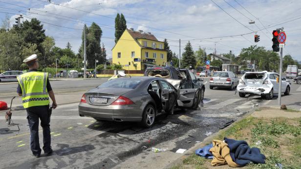 Ein Verkehrsunfall mit mehreren beschädigten Autos auf einer Kreuzung, ein Polizist steht daneben.
