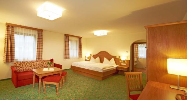 Einladendes Hotelzimmer mit Doppelbett, Sofa und grünem Teppichboden.