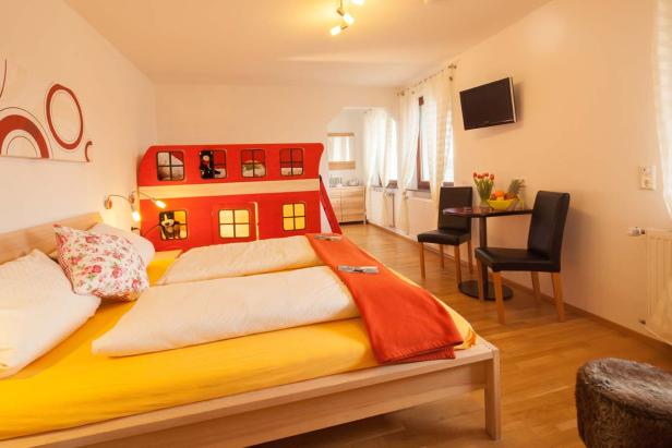 Ein Zimmer mit einem Bett und einem roten Bus als Kopfteil.