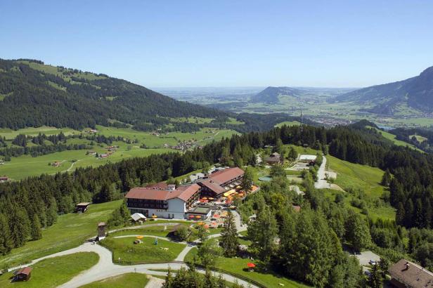 Ein Hotel liegt auf einem Hügel mit Blick auf eine grüne Landschaft.
