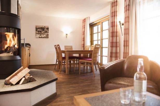 Ein Wohnzimmer mit Kamin, Esstisch und einem Sessel mit einer Flasche darauf.